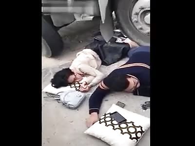 COUPLE RELAXING WHILE THEY ARE UNDER A TRUCK TIRE