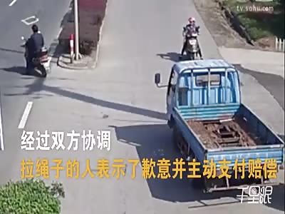 Woman riding on a scooter gets flown off after the wheel gets tangled with a rope 