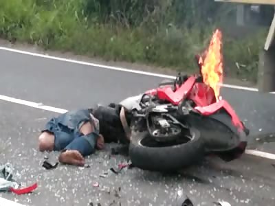 Dead Man and Burning Motorbike in the Road as People Drive by