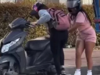 Women Trying to Figure out a Kickstand on a Moped